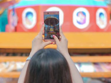 woman holding iphone 6 taking photo of yellow and red building